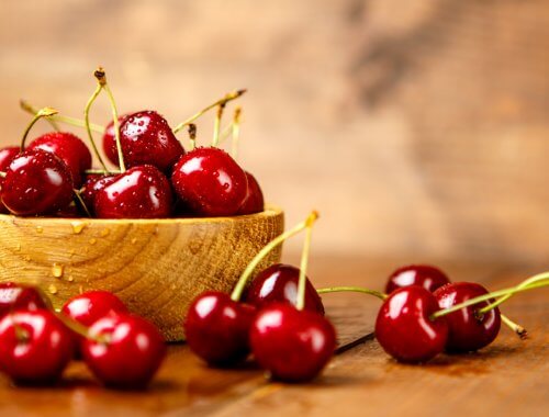 primer plano de mesa con un cuenco de cerezas