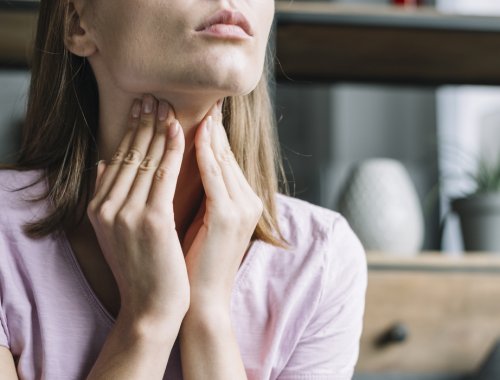 mujer tocándose el cuello, donde se encuentra la tiroides