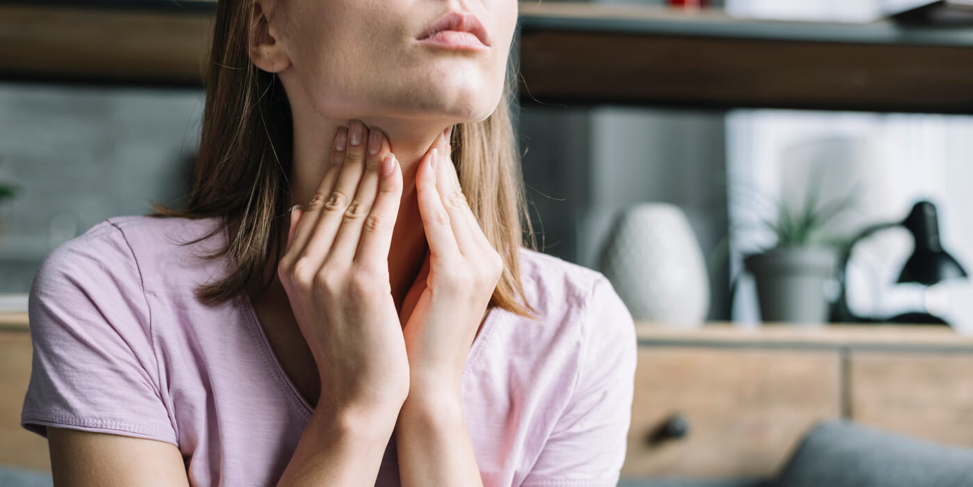 mujer tocándose el cuello, donde se encuentra la tiroides