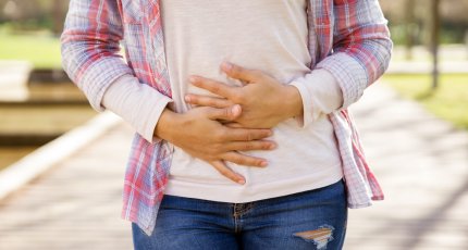 mujer apretándose el abdomen mostrando dolor