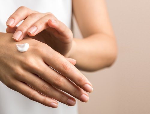 Mujer aplicándose crema en una mano